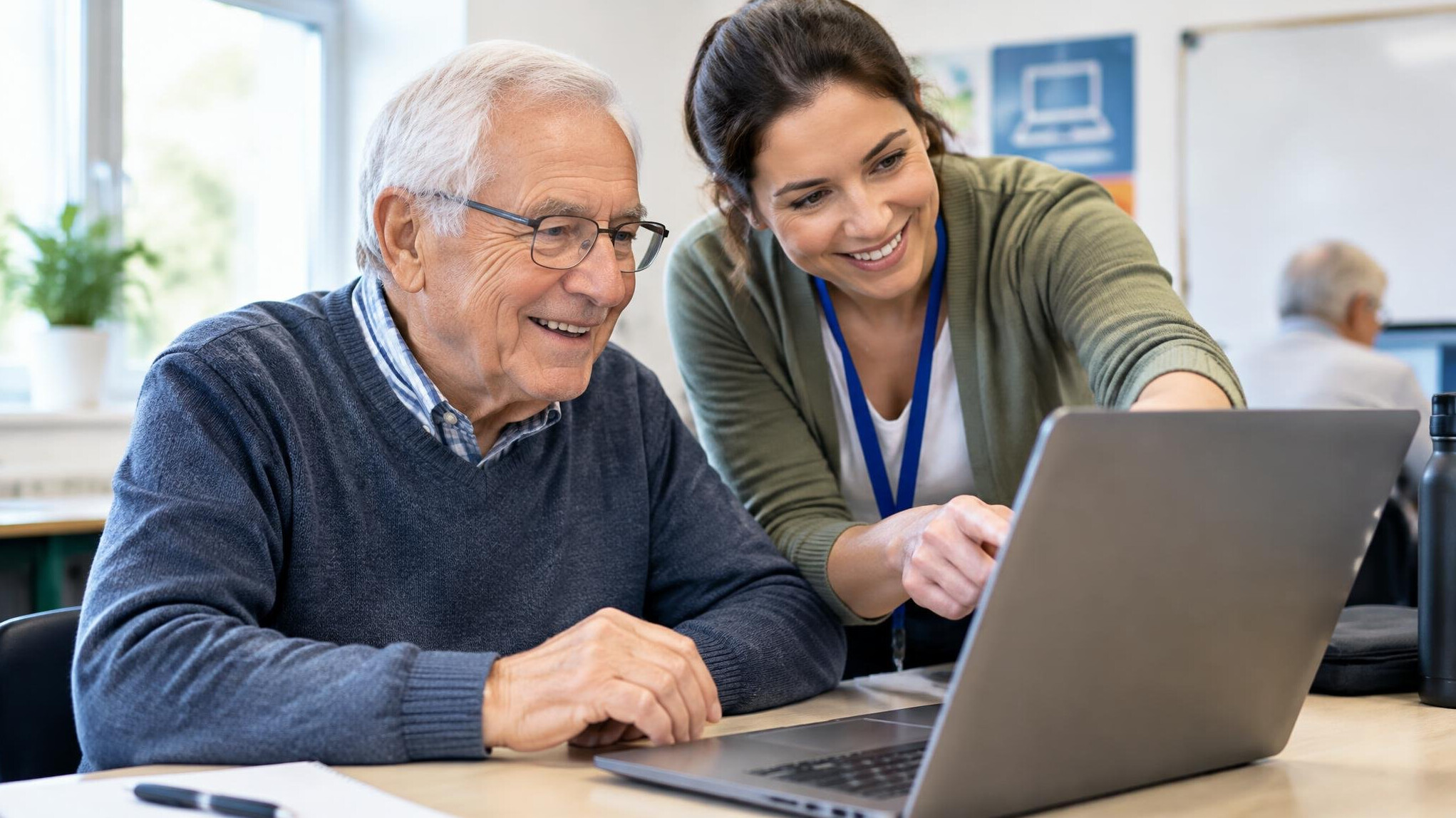 Senior European man learning to use a laptop with help from a younger instructor
